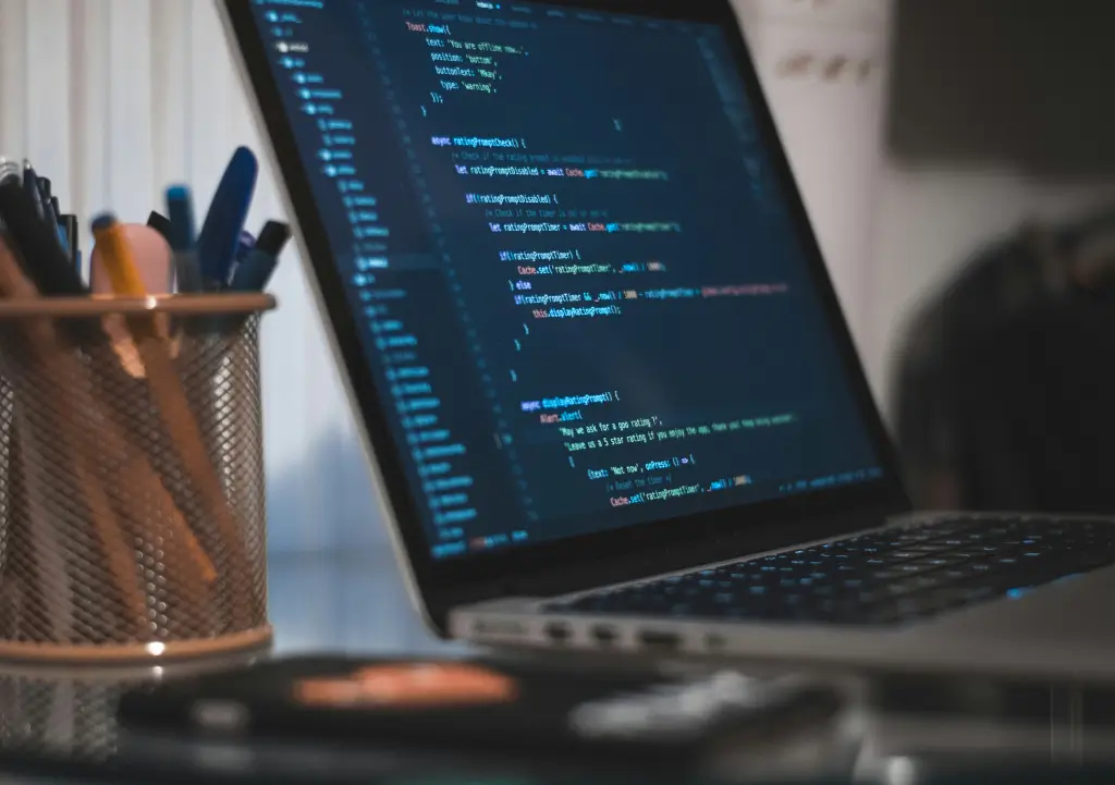 Un ordinateur portable ouvert sur lequel est affiché du code source. Le développement sur mesure offre des fonctionalités robustes pour un budget maîtrisé.